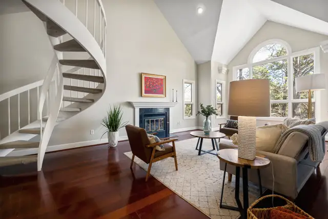 Living room with a fireplace, spiral staircase and tall windows