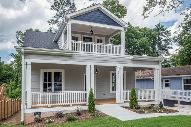 White two-story house with a wraparound porch and new lawn